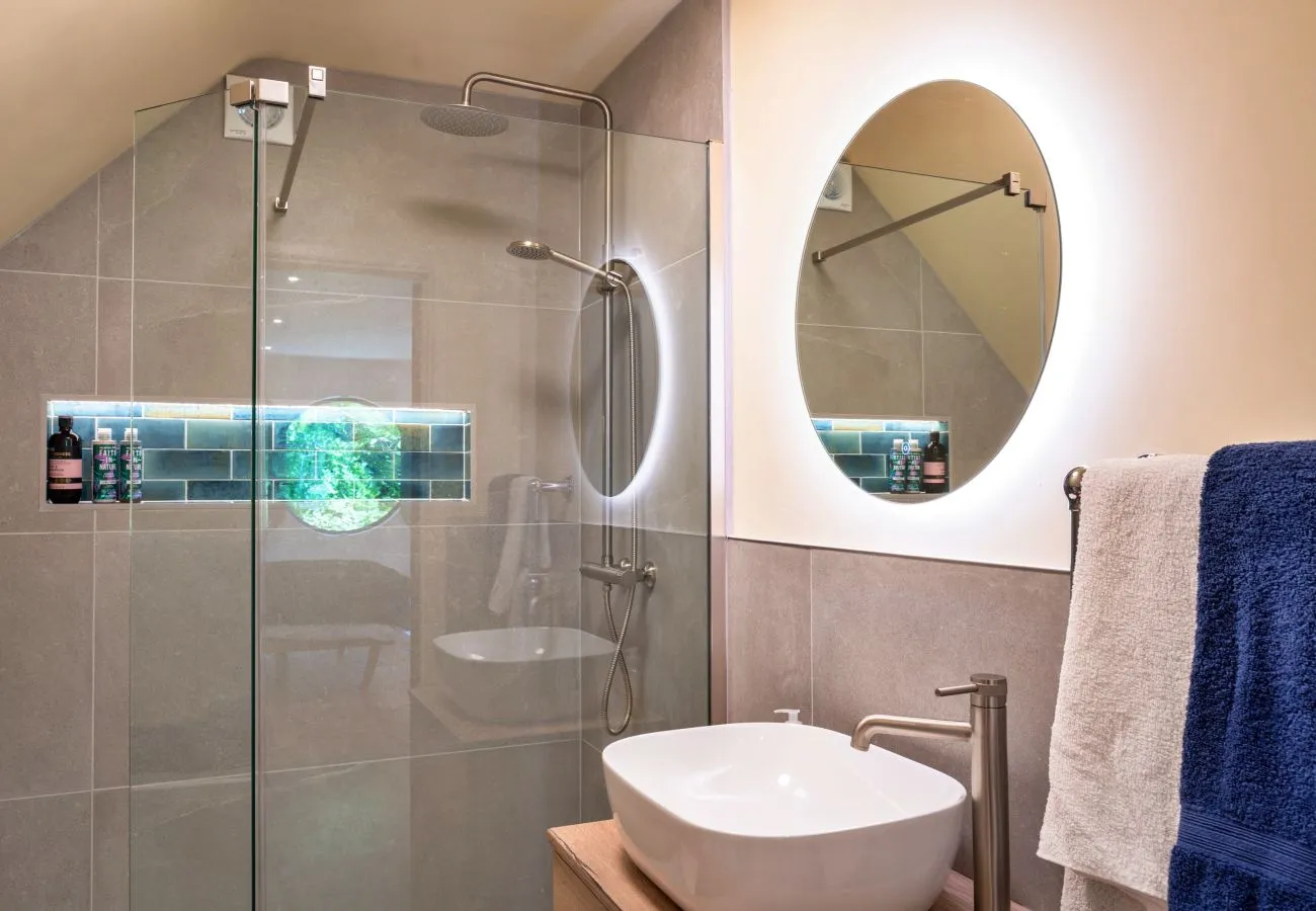 En-suite shower room with walk-in shower and backlit round mirror