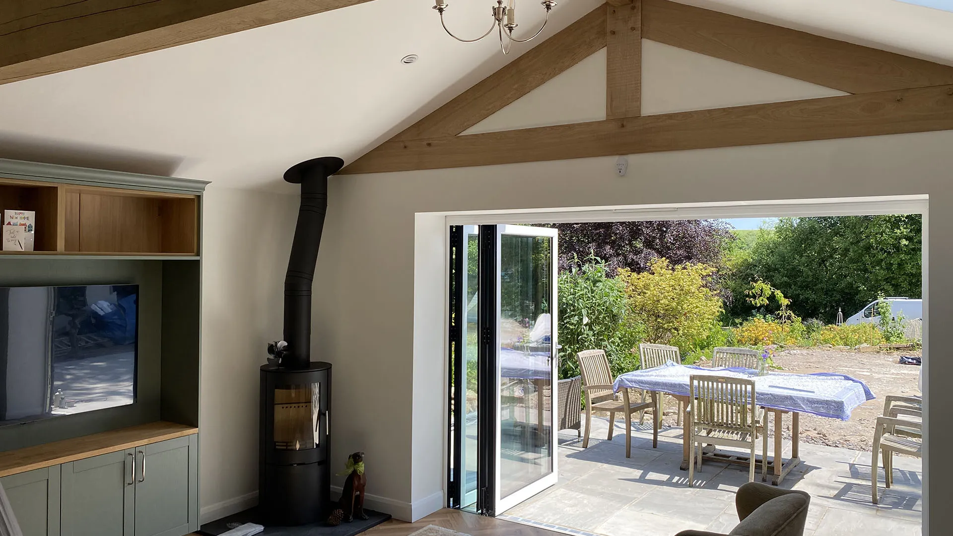 Oak framed living space with a woodburner and bifold doors opening to the garden